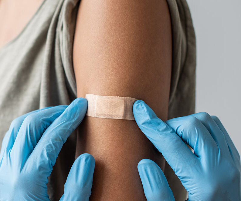 Eine Frau bekommt ein Pflaster auf den Oberarm geklebt.