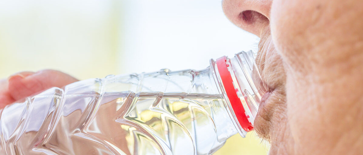 Nahaufnahme einer Seniorin, die aus einer Wasserflasche trinkt