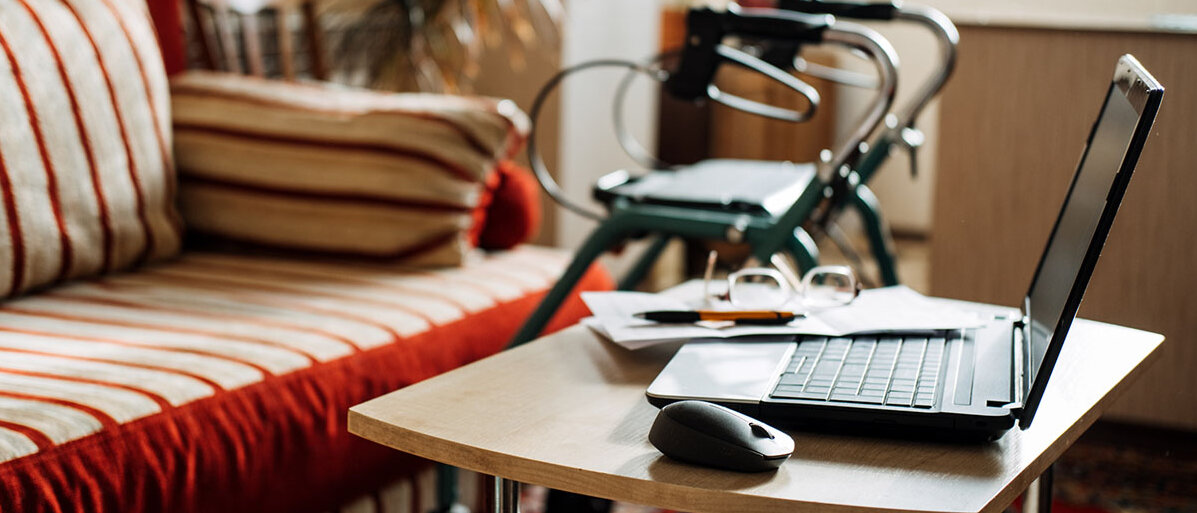 StĂĽrze mit Rollator vermeiden Wohnzimmer mit Sofa, Couchtisch und Laptop, im Hintergrund ein Rollator