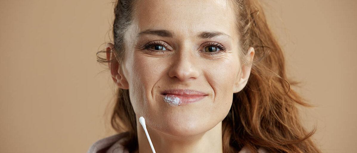Neues Medikament zur Behandlung von Herpes: Pritelivir Eine Frau hat mit einem Wattestäbchen Lippenherpes-Creme aufgetragen.