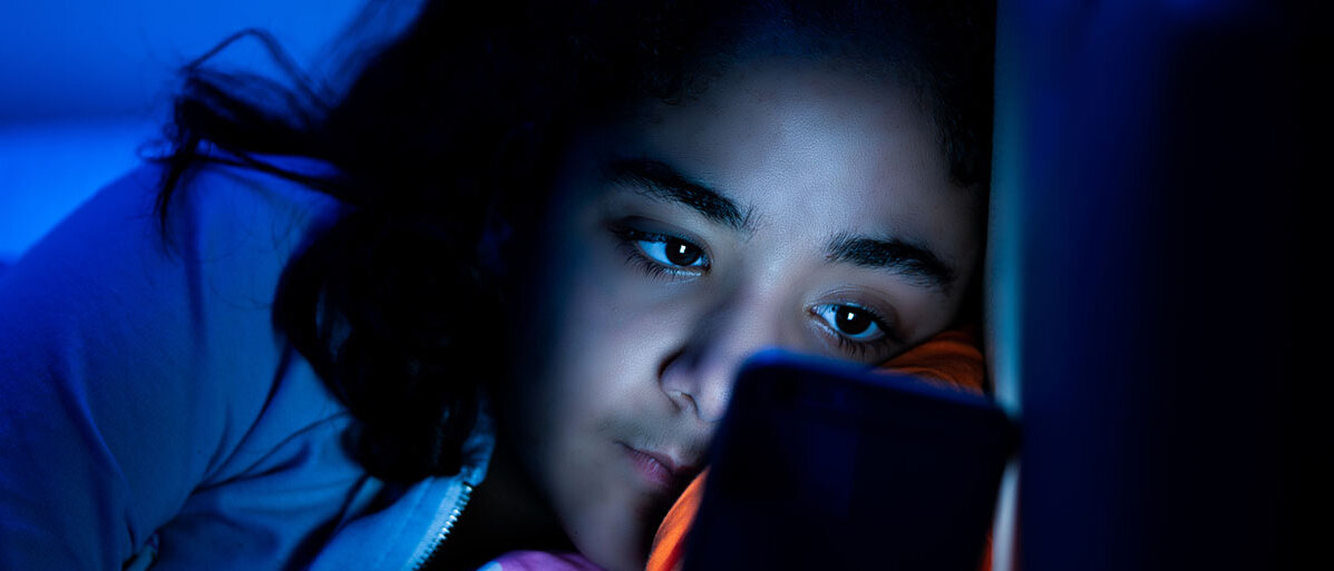 Junges Mädchen mit Smartphone im Bett