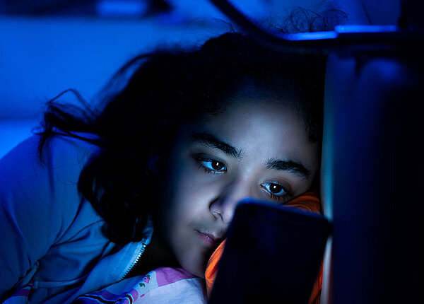 Junges Mädchen mit Smartphone im Bett