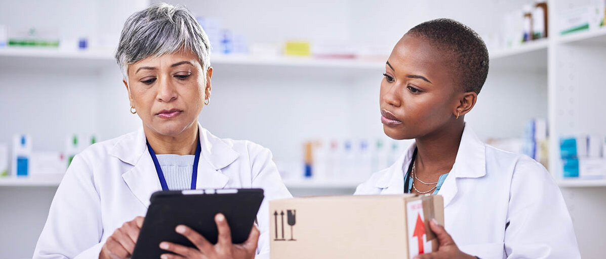 Rossmann als Versandapotheke: Auch Rezepte soll man online einlösen können. Zwei Apothekenmitarbeiterinnen verpacken im Lager ein Päckchen für den Versand und schauen dabei auf ein Tablet.