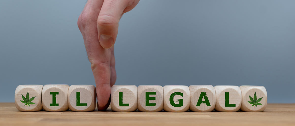 Würfel bilden das Wort "ILLEGAL", während eine Hand die Buchstaben "IL" trennt, um das Wort in "LEGAL" zu ändern.