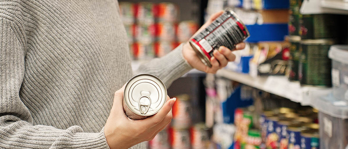 Bisphenol A (BPA) in Konservendosen hat eine hormonähnliche Wirkung. Bis das Verbot greift, eignen sich Konserven im Glas. Eine Frau steht im Supermarkt vor dem Regal mit den Konserven und hält zwei Dosen in der Hand.