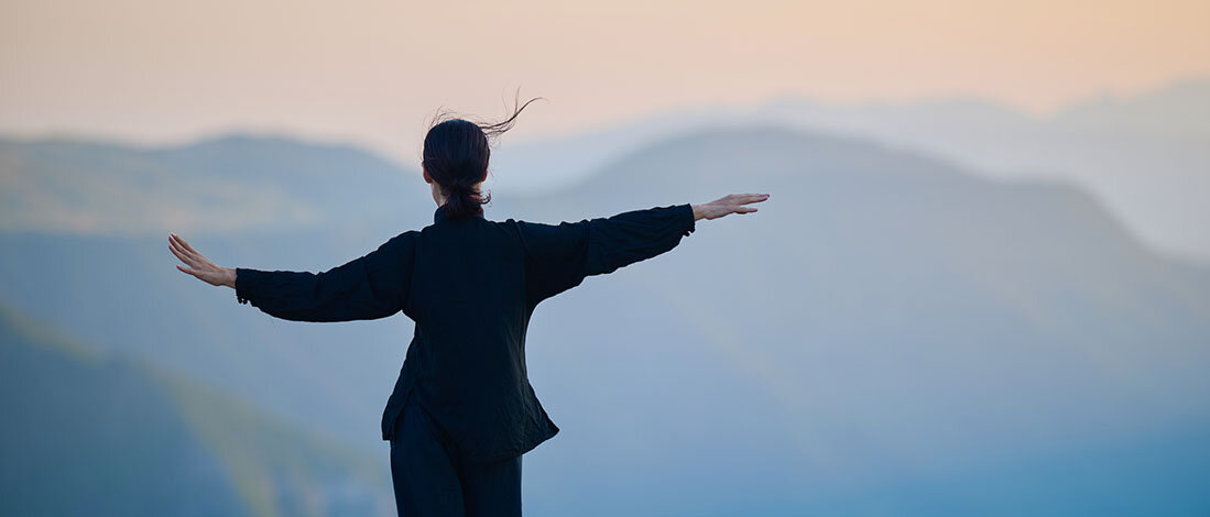 Frau mit ausgestreckten Armen auf Berg