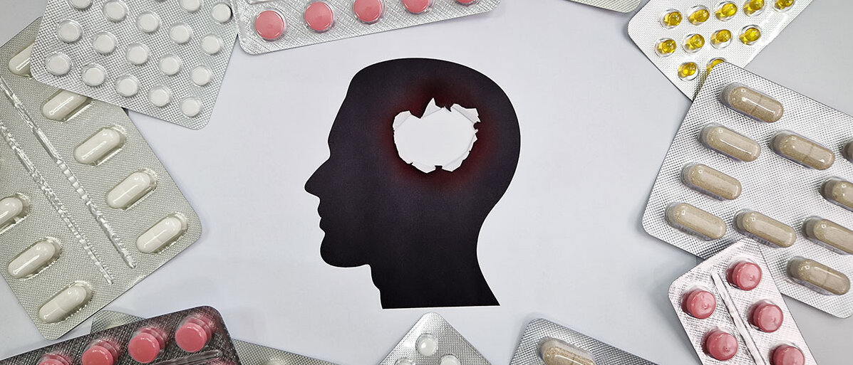 Silhouette eines Kopfes mit Loch darin, darum verteilt Blister mit unterschiedlichen Tabletten