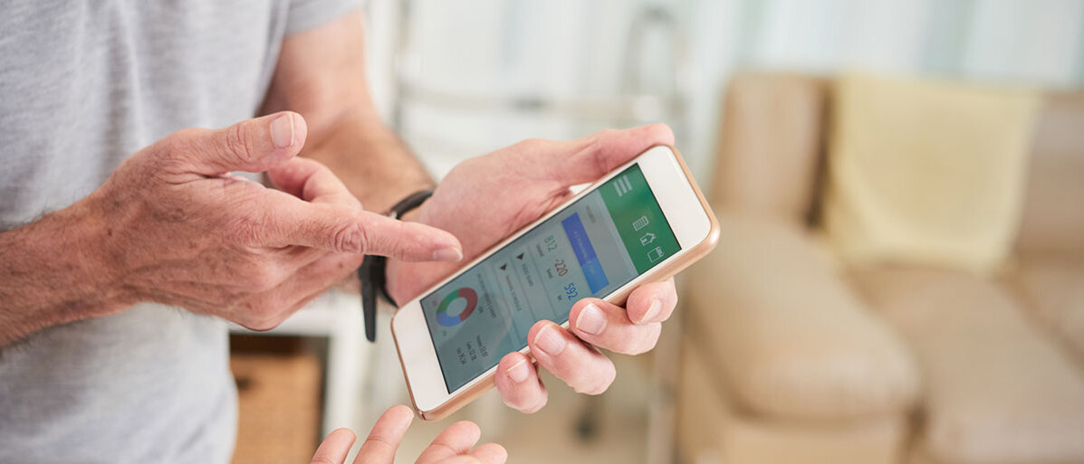 Mann hält Handy in der Hand und zeigt das Display einer Ärztin