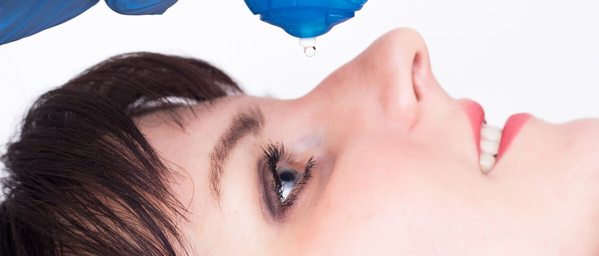 Fremdkörper im Auge sicher entfernen Ärztehand tropft Augentropfen in das Auge einer liegenden Frau