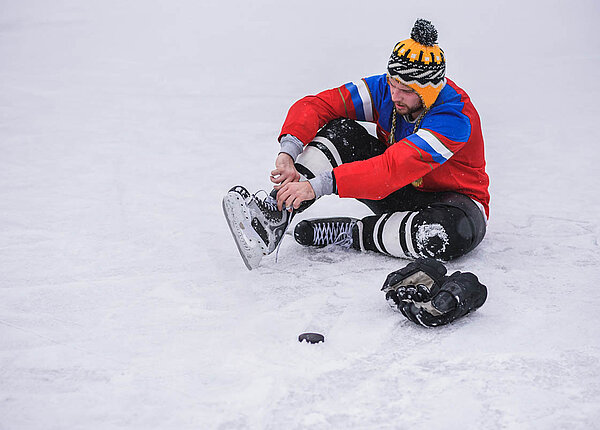 Senf gegen Muskelkämpfe: Was ist dran an Leon Draisaitls Tipp gegen Krämpfe beim Sport? Ein Eishockeyspieler sitzt auf dem Eis, hat ein Bein aufgestellt und schnürt seinen Schlittschuh.