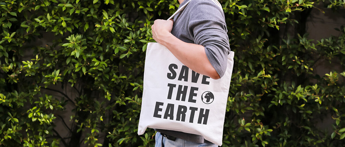 Ein Mann hat einen Stoffbeutel um die Schulter gehängt, auf dem Save the Earth steht.