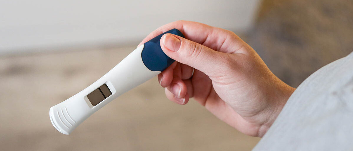 Macht die Spirale unfruchtbar? Jemand hÀlt einen digitalen Schwangerschaftstest in der Hand. Darauf ist nur ein Strich zu sehen, er ist negativ.