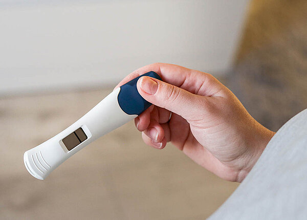 Jemand hält einen digitalen Schwangerschaftstest in der Hand. Darauf ist nur ein Strich zu sehen, er ist negativ.