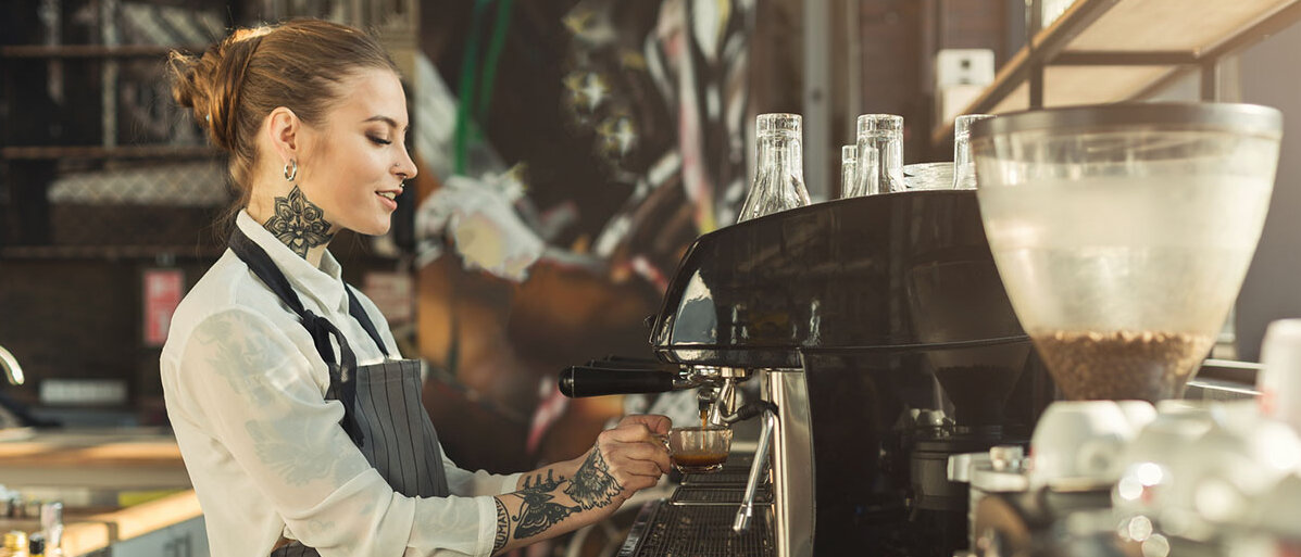Eine Barista bereitet an einer großen Siebträgermaschine einen Espresso zu.
