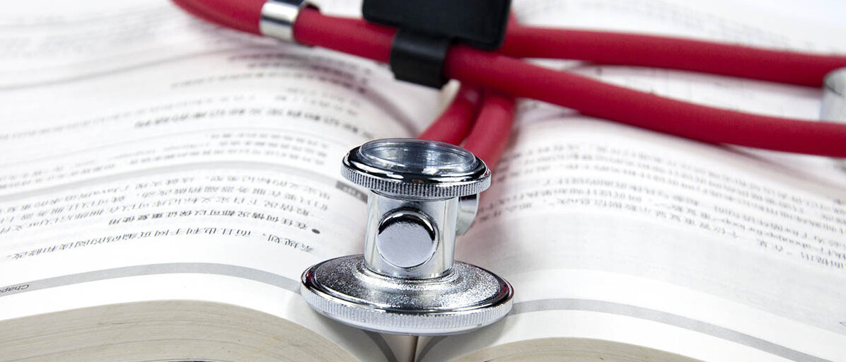 Ein aufgeschlagenes buch zeigt chinesische oder japanische Schriftzeichen. Darauf liegt ein Stethoskop.