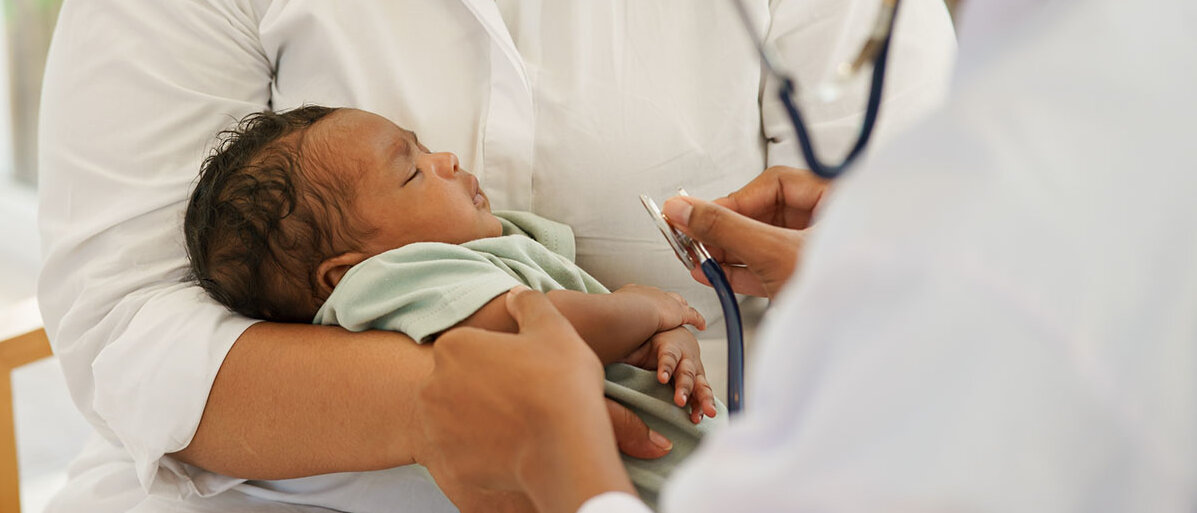 Neugeborenes Kind auf dem Arm der Mutter wird vom Arzt untersucht