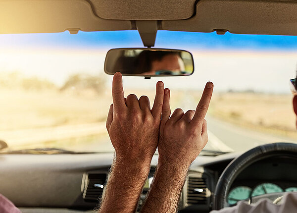 Zwei Freunde im Auto machen Handzeichen