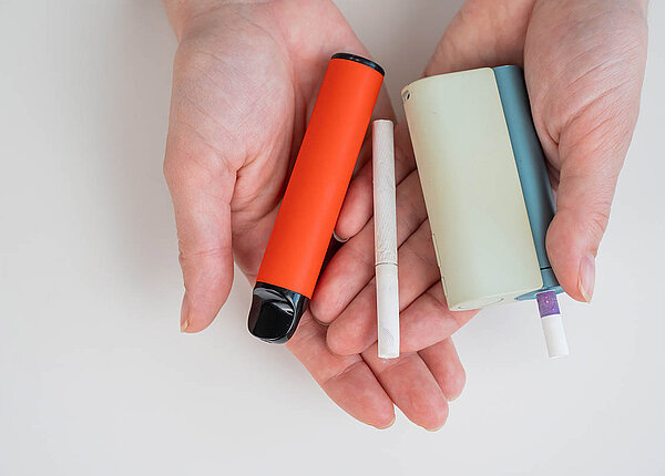 Raucherentwöhnung mit E-Zigaretten ist besser geeignet als andere Rauchstopp-Methoden um mit dem Rauchen aufzuhören Eine Frau mit normaler, elektronischer Zigarette und Einweg-Vape