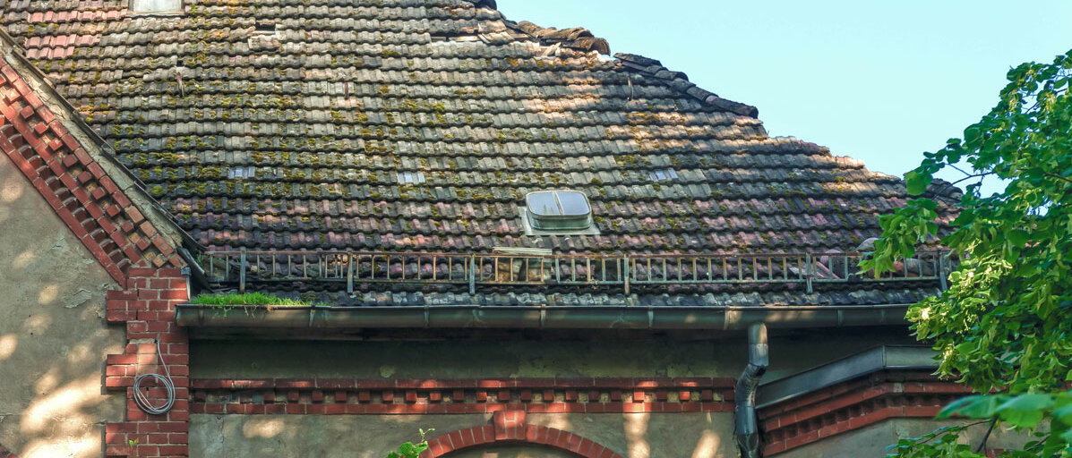 Ein altes Haus hat ein Dach mit losen Schindeln und Löchern.