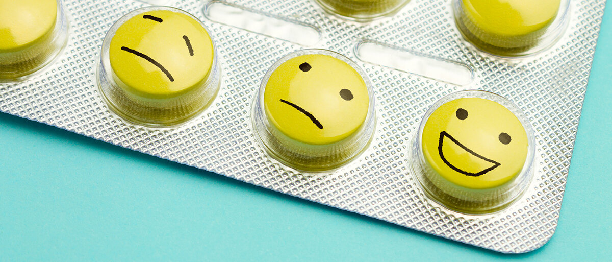 Ein Blister mit gelben Tabletten. Auf den Tabletten sind unterschiedliche Smileys aufgemalt