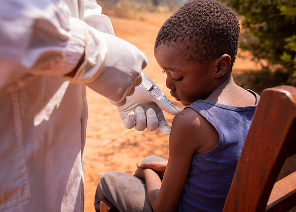 Neue Studie zu Malaria Impfungen bei Kindern in Afrika Arzt impft afrikanischen Junge in die Schulter