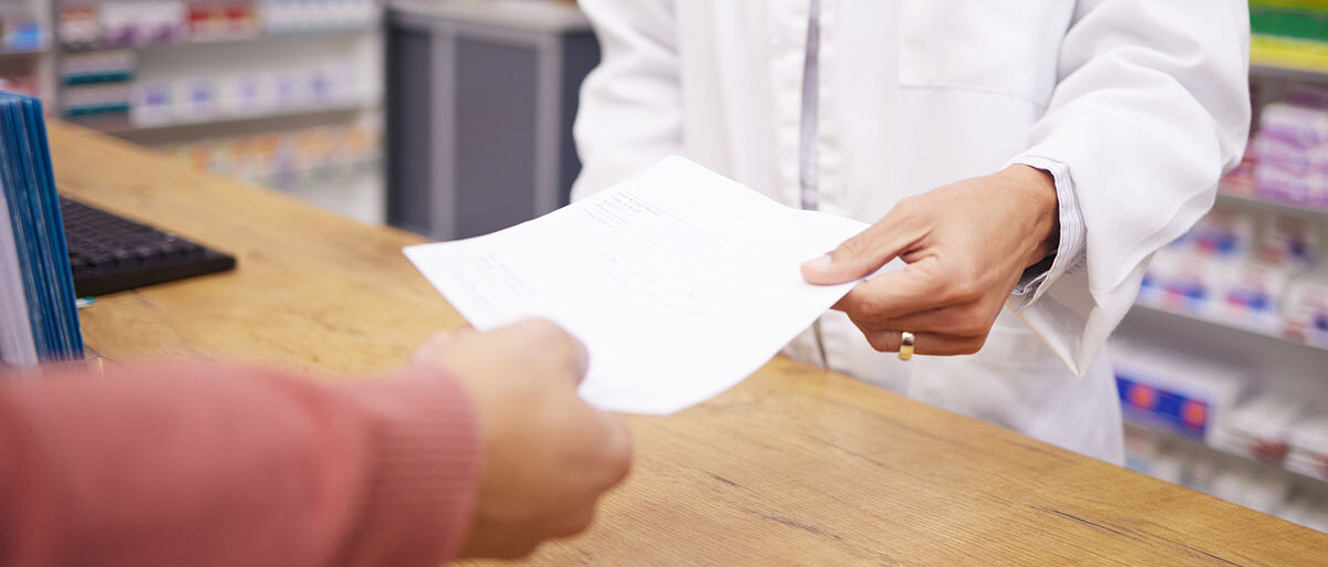 Apothekerin händigt Kunden Zettel aus