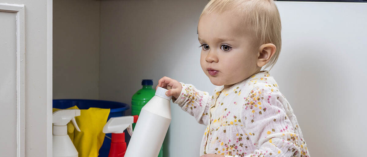 Erste Hilfe bei Vergiftung: Symptome erkennen und behandeln oder im Notfall den Giftnotruf wĂ€hlen Ein kleines Kind nimmt eine Flasche mit Haushaltsreiniger aus dem SpĂŒlschrank.