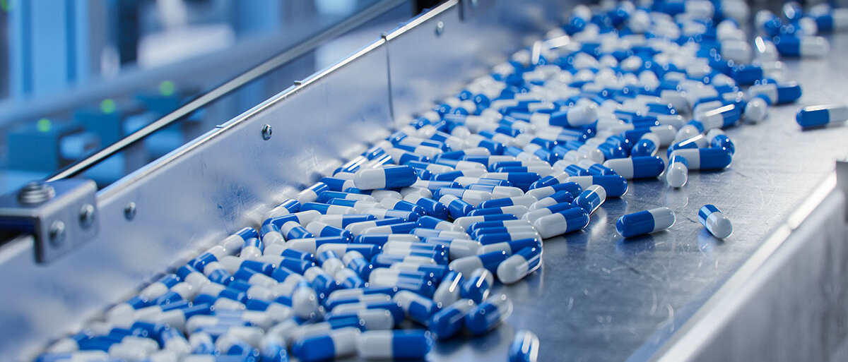 Blau-weiße Arzneimittelkapseln auf einem Laufband
