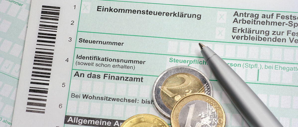 Außergewöhnliche Belastungen in der Steuererklärung Einkommensteuererklärung mit Münzen und Stift