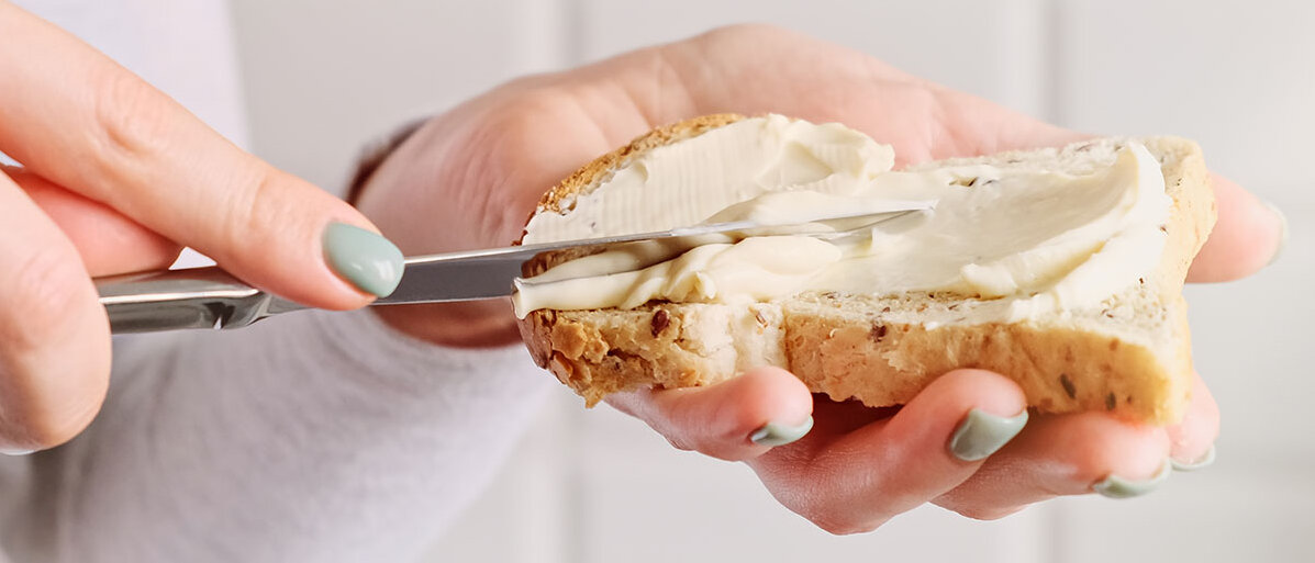 Frau bestreicht Brotscheibe mit Butter oder Margarine 