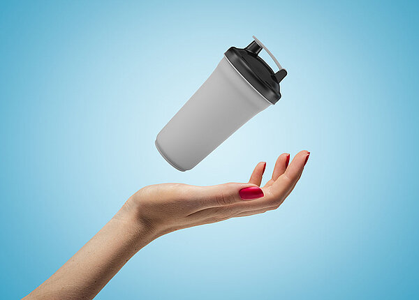 Nahaufnahme einer Hand, die einen Shaker in der Hand nach oben wirft