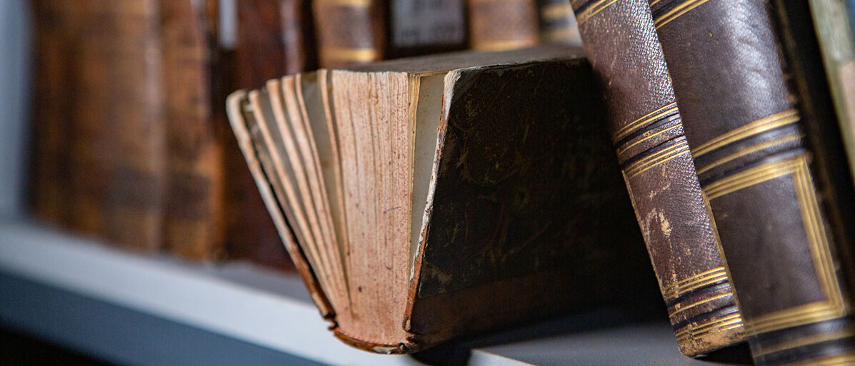 Alte Bücher mit vergilbten Seiten und Ledereinbänden in einem Regal