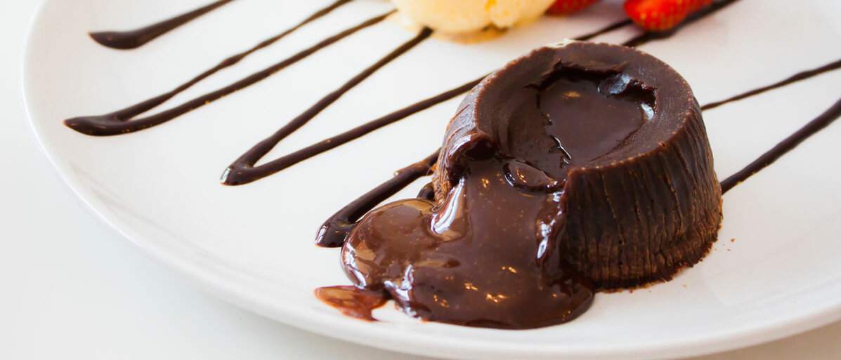 Schokoladenkuchen aus dem fluessige Schokolade läuft auf einem Teller platziert