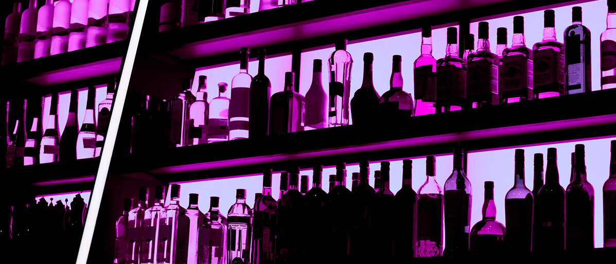 Eine lila eingefärbte Bar mit vielen Flaschen.