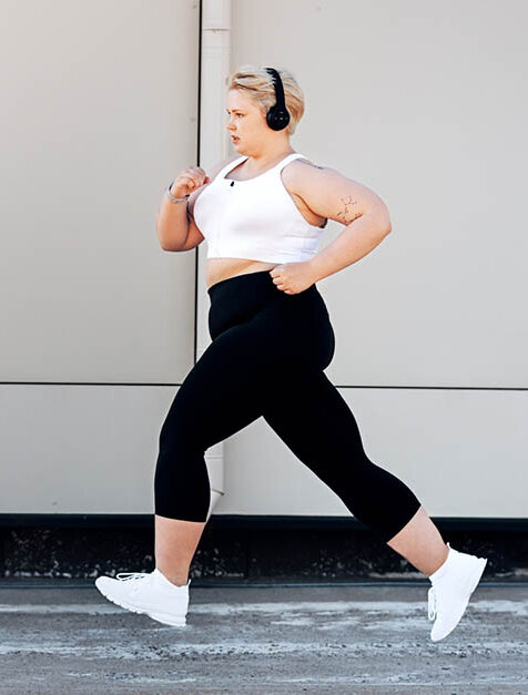 Eine junge, übergewichtige Frau joggt. Sie hört dabei Musik.