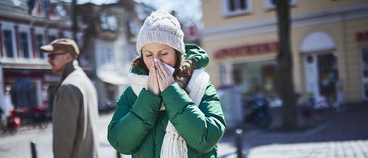 Frau putzt sich die Nase.