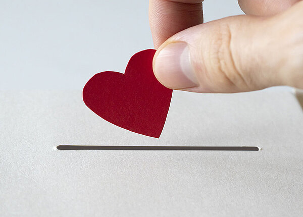 Papier-Herz wandert in Sparschlitz 