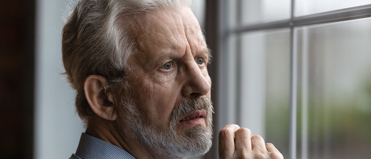 Verwirrtheit nach einer Operation. Älterer Mann steht am Fenster und schaut nach draußen