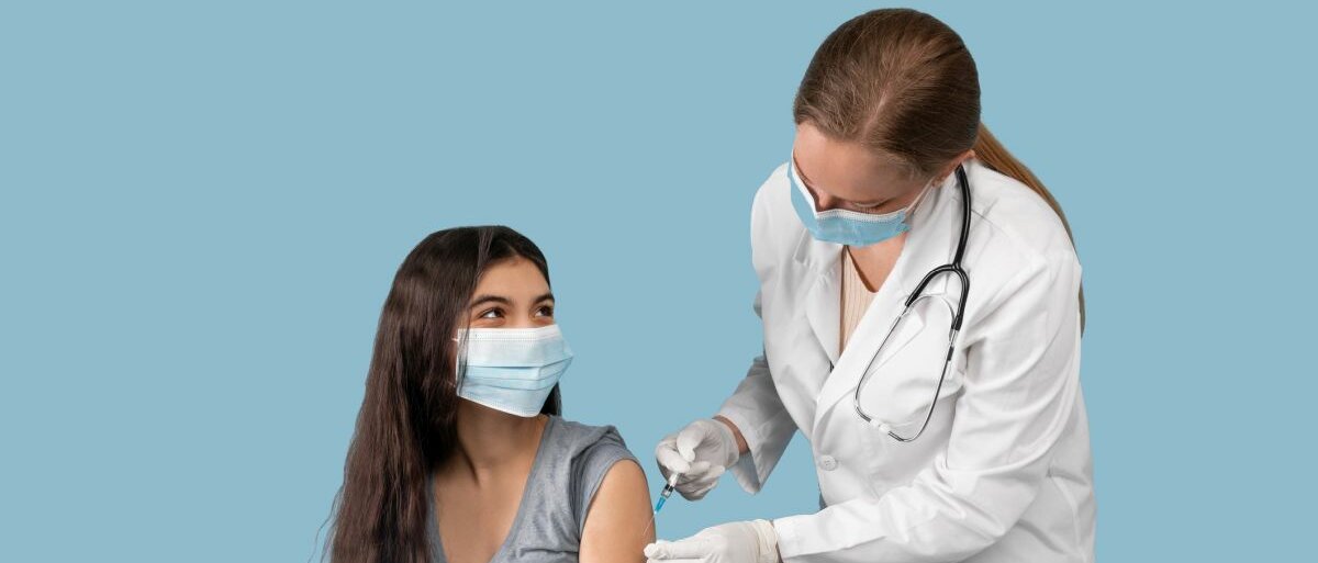 Eine Ärztin, die ein junges Mädchen vor blauem Hintergrund impft.