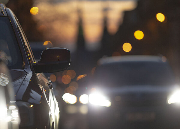 starker Autoverkehr in der Abenddämmerung, dass von vielen Scheinwerfern und Stadtlichtern beleuchtet wird.