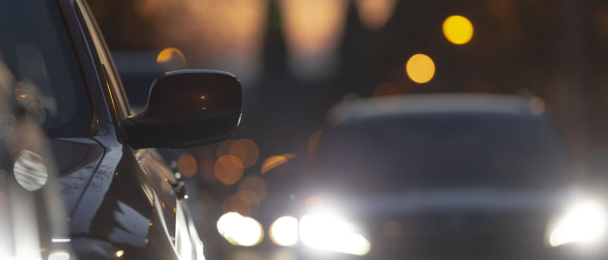 starker Autoverkehr in der Abenddämmerung, dass von vielen Scheinwerfern und Stadtlichtern beleuchtet wird.