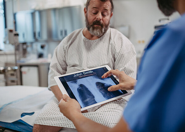 Arzt zeigt übergewichtigem Patienten Röntgenbilder der Lunge