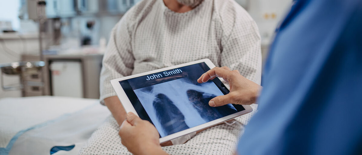 Arzt zeigt übergewichtigem Patienten Röntgenbilder der Lunge