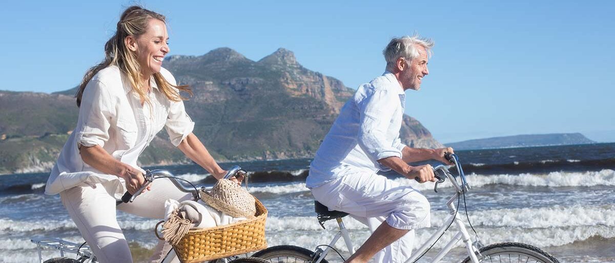 Mann und Frau fahren Fahrrad am Strand.