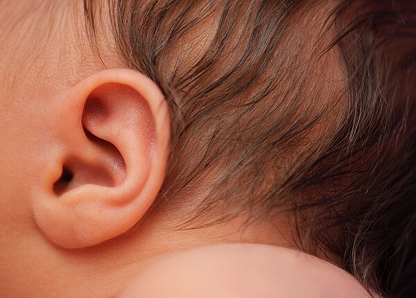 Ohr eines Neugeborenen mit braunen Haaren