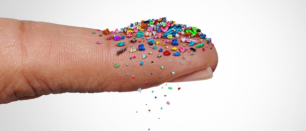 Winzige, bunte Plastikteile rieseln von einer Fingerspitze