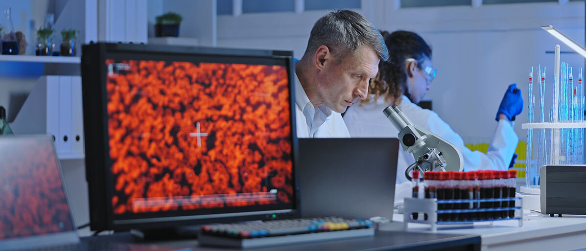 Forscher untersucht Blutzellen unter einem Mikroskop.