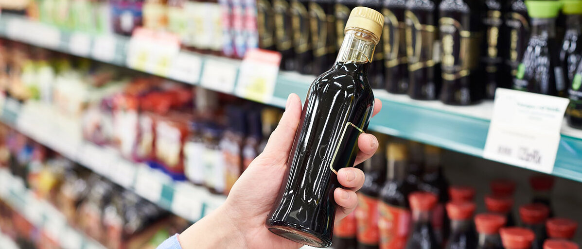 Sojasauce Frau hält vor Supermarktregal Sojasauce in der Hand