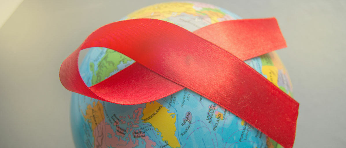 Auf einer runden Weltkarte liegt eine rote Schleife