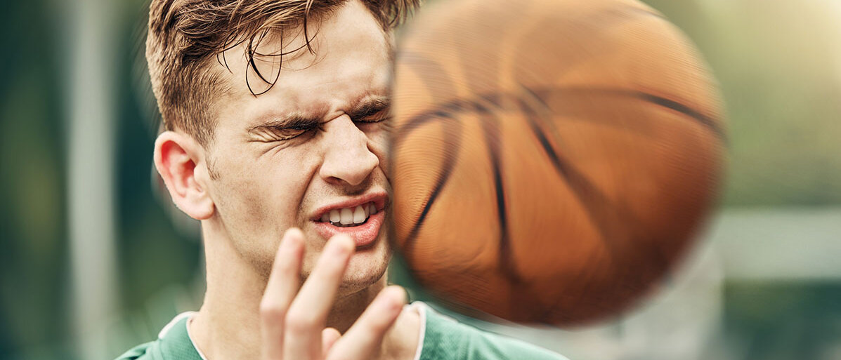 Ein Basketball trifft einen jungen Mann am Kopf.